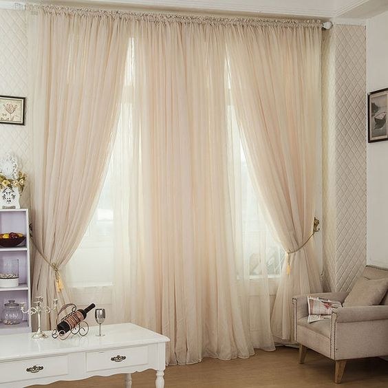 Sage green and floral patterned curtains in a bedroom with wooden furniture and plants.