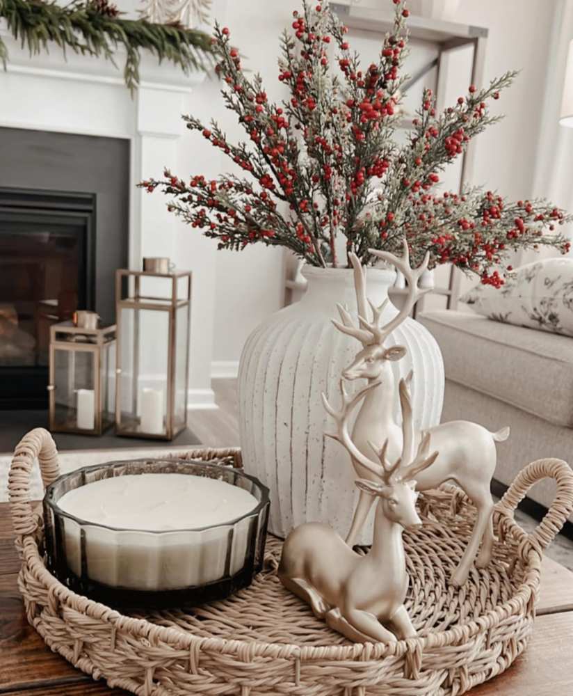 Metal tray with red berry branches and brass deer figurine on wooden coffee table.