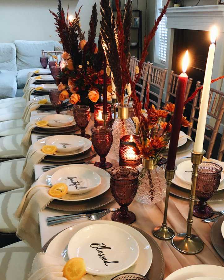 Dining table with “Blessed & Grateful” sign, neutral linen, wooden chargers, soft candlelight, autumn leaves