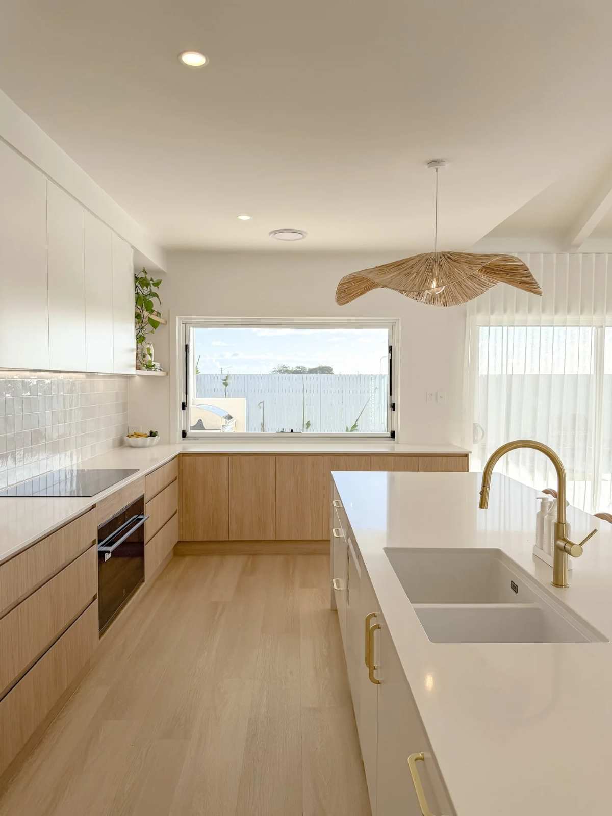 Bright kitchen with light blonde wood cabinets, white quartz countertop, sea‑foam glass backsplash, natural rope lighting.