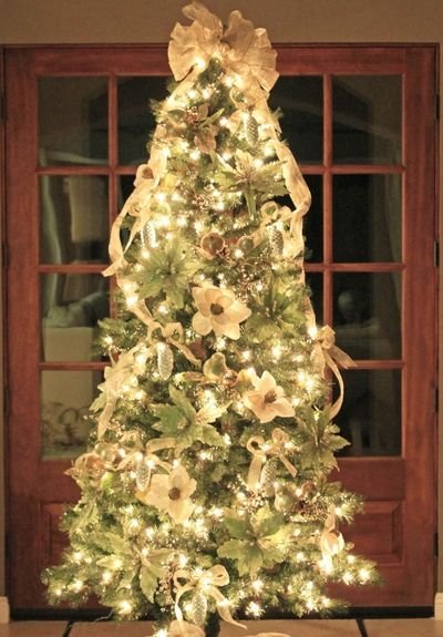 Living room Christmas tree featuring slate blue linen ribbon, linen sofa, warm fireplace light