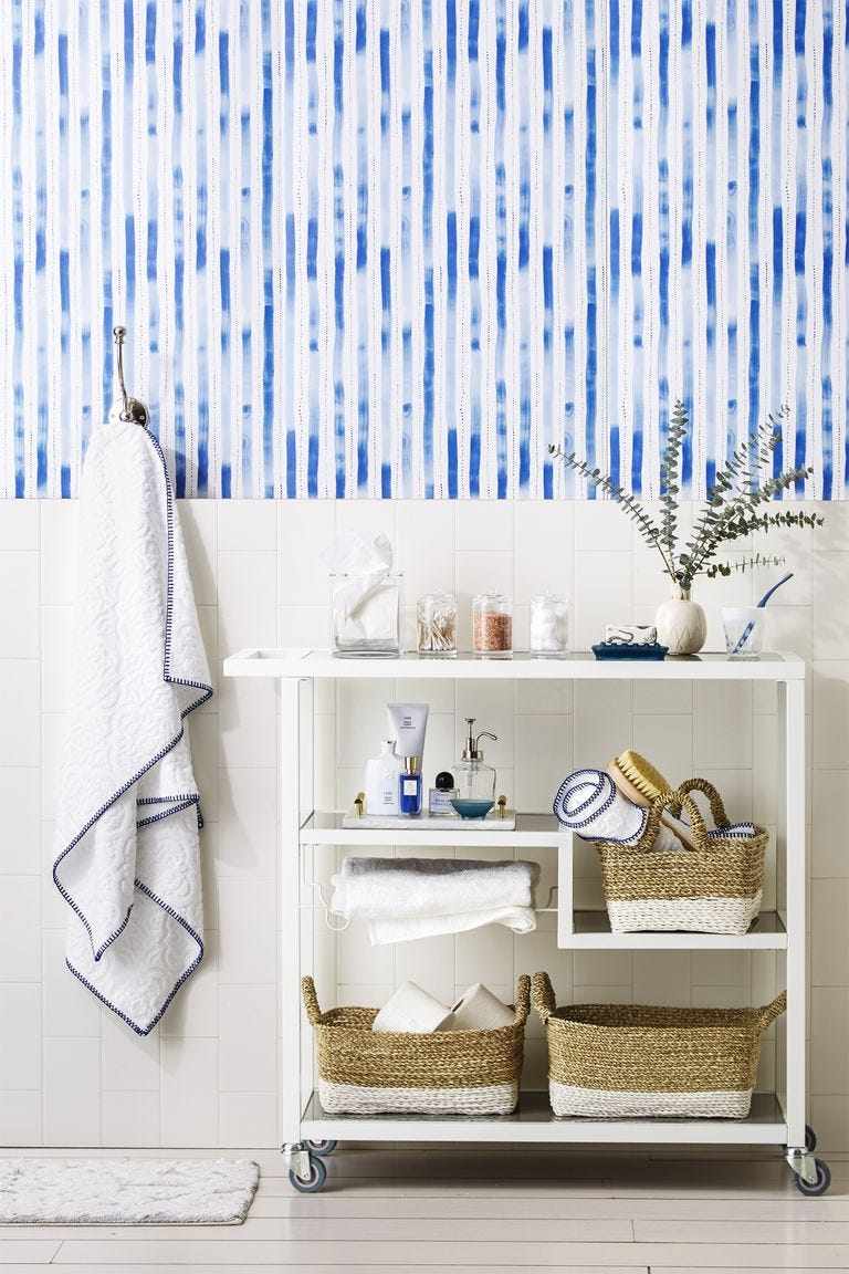 Pale blue candy striped wallpaper styled with open natural oak floating shelves and brass brackets