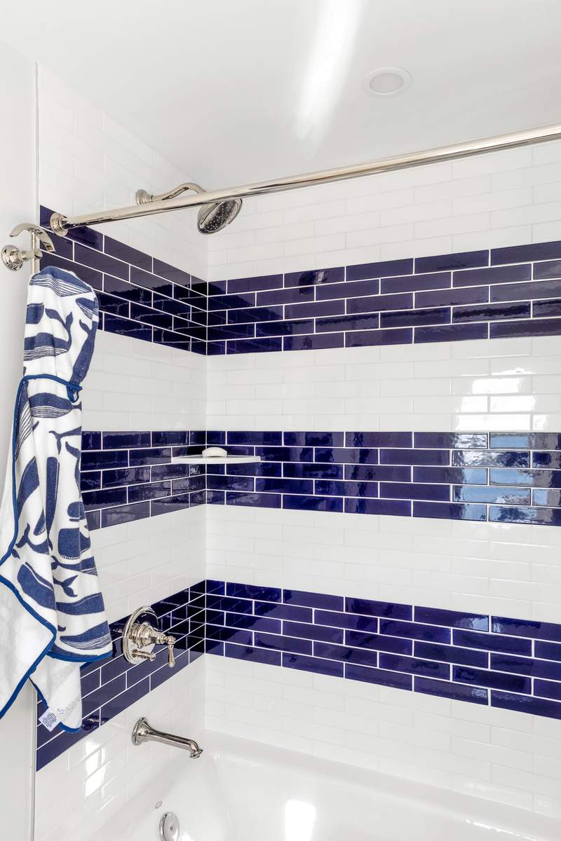 Handcrafted dark blue zellige subway tile shower wall with brushed nickel fixtures and frameless glass door