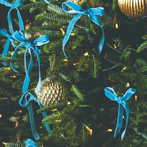 Formal living room tree dressed with navy blue velvet ribbon, brass floor lamp lighting