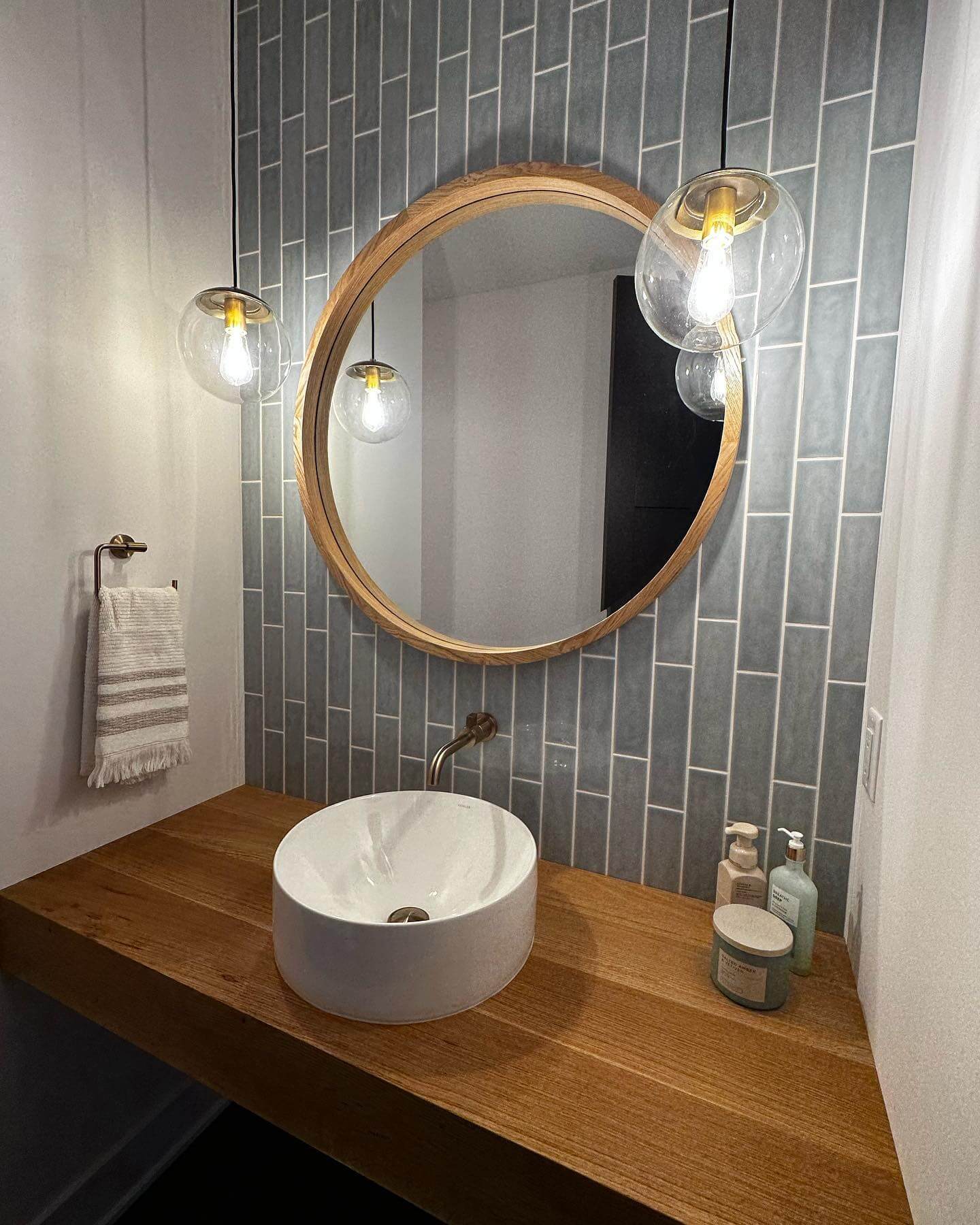 Half bathroom with vertical blue subway tiles, white vessel sink, chrome fixtures.