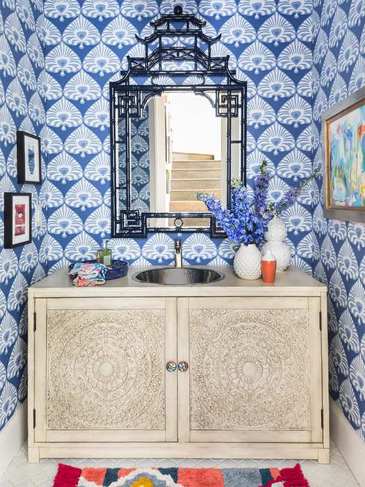 Delicate powder blue damask wallpaper framing a clean white vanity with brushed gold hardware