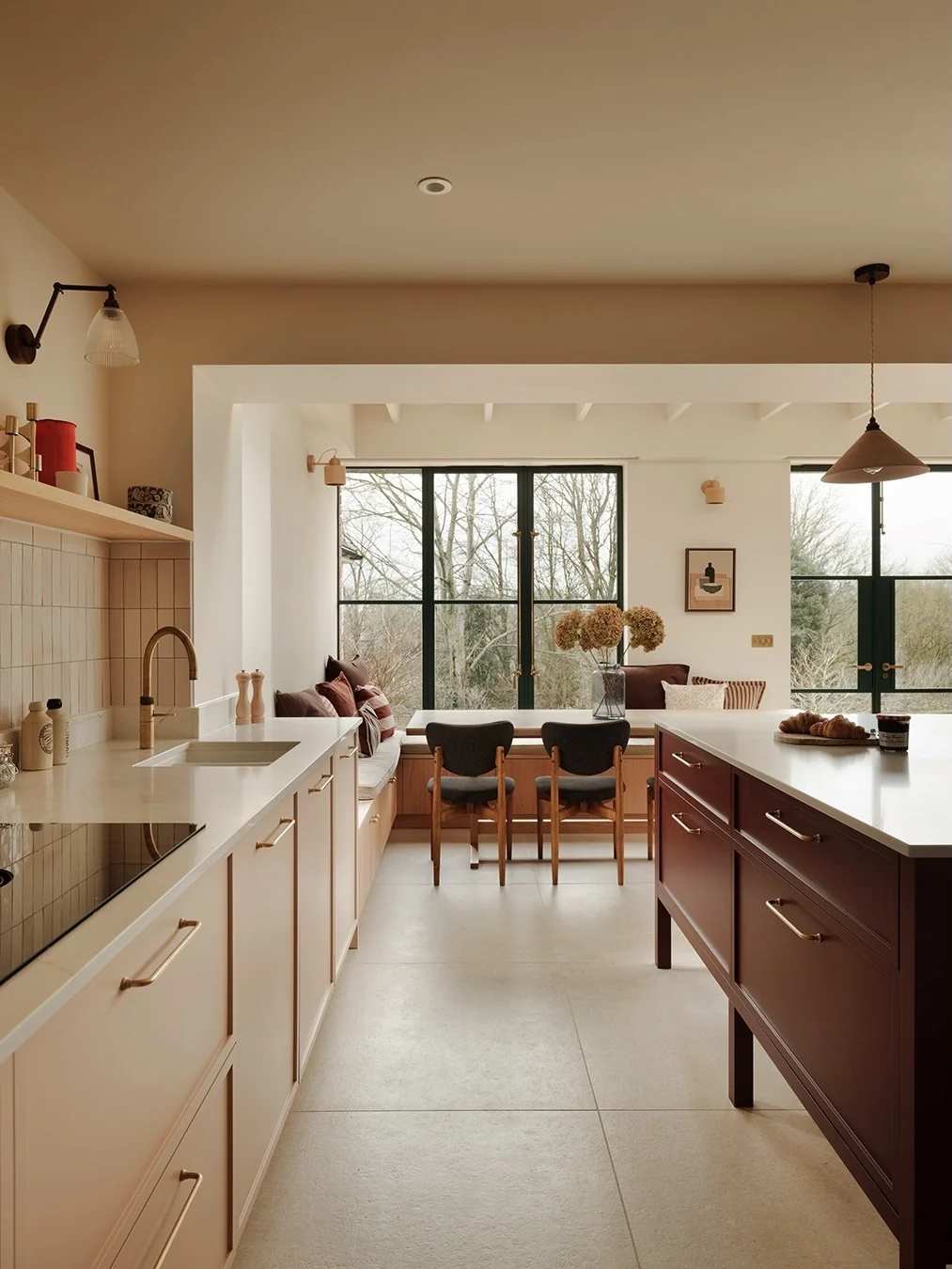 Kitchen featuring blush beige walls, chestnut wood island, brushed gold fixtures, matte black appliances.