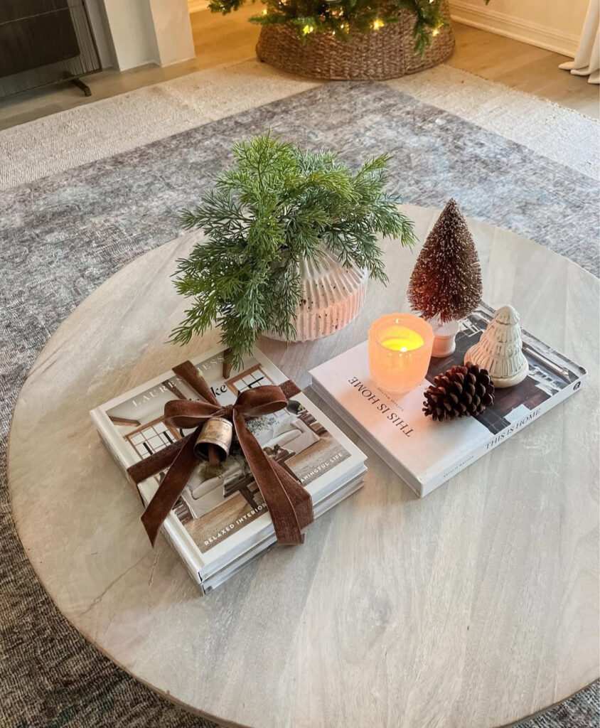 Stacked white coffee table books tied with deep green velvet ribbon and pine sprigs.