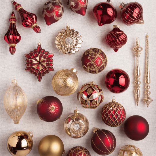 Deep bordeaux red and metallic gold ornaments on a tree branch with warm lighting.