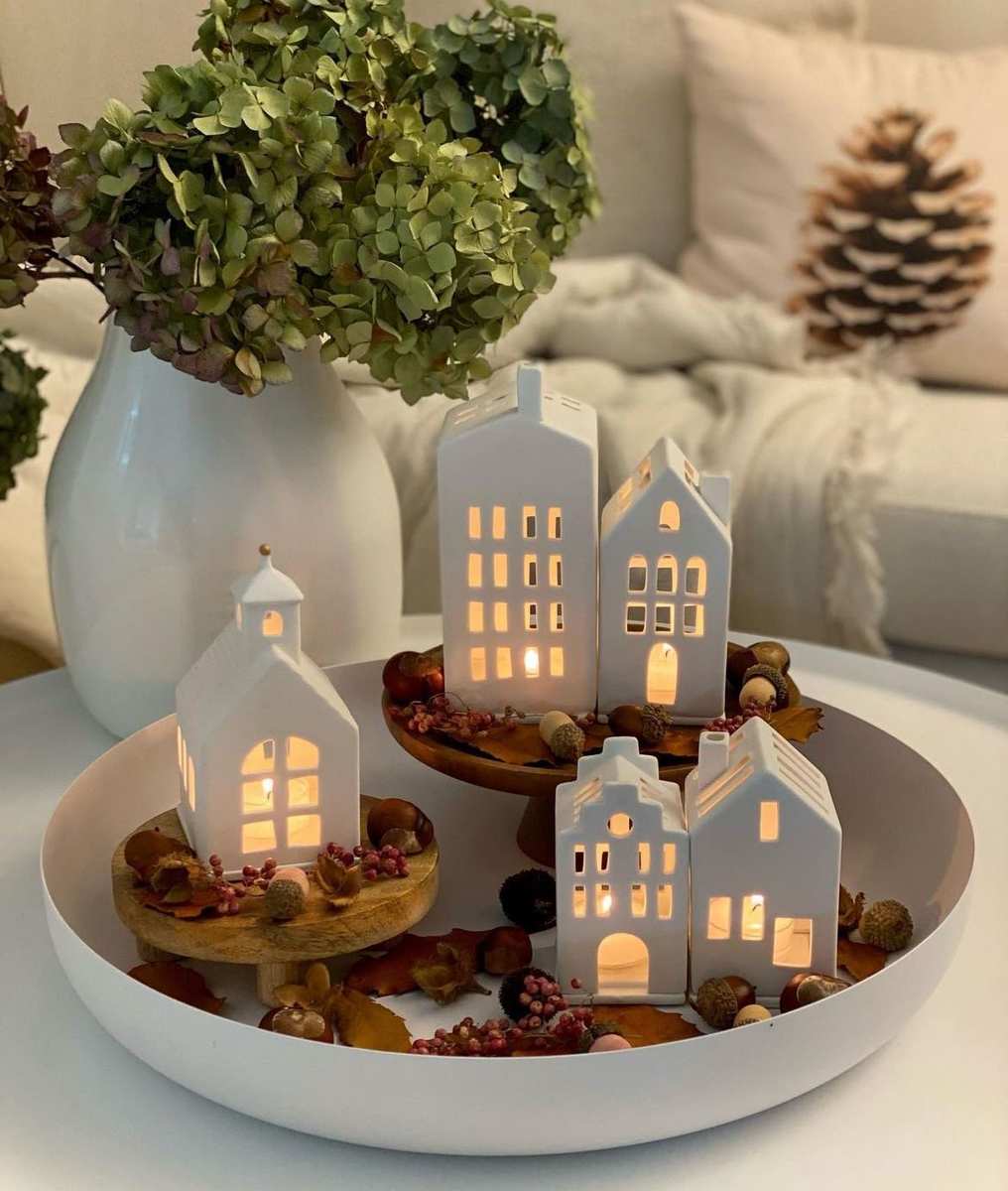Large ceramic bowl filled with gold and glass christmas ornaments on living room table.