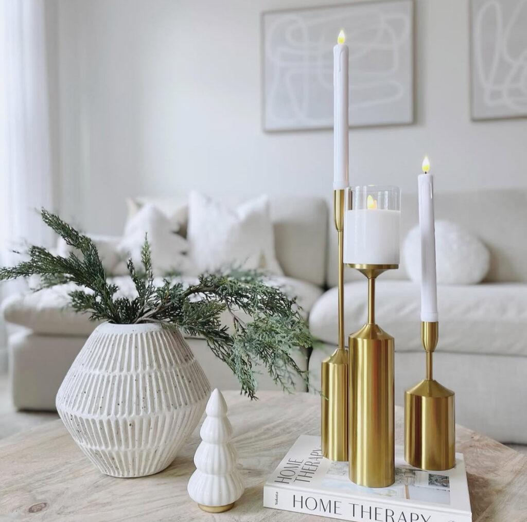Brass candle holders with tall white taper candles on a marble coffee table.