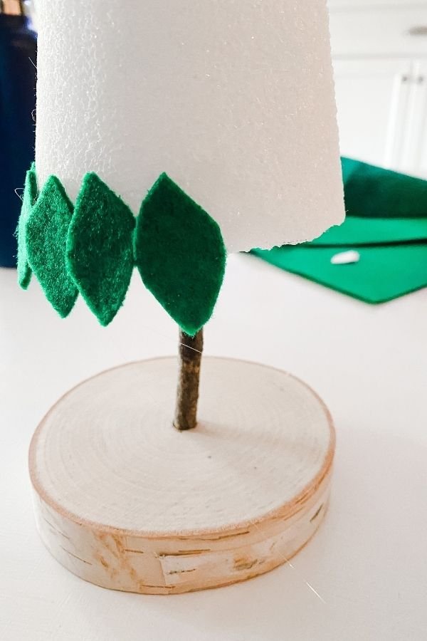Entryway oak console table adorned with neutral oatmeal felt christmas trees, ceramic vase, and amber lighting.