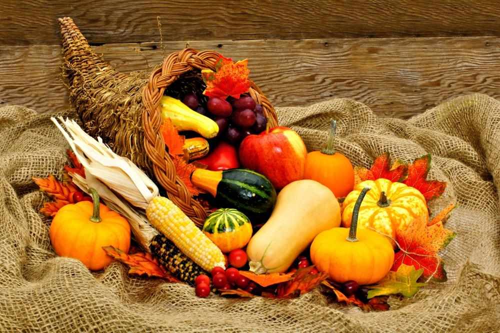 Farmhouse dining room, burlap cornucopia, pumpkins, corn, burlap tablecloth, warm overhead light.
