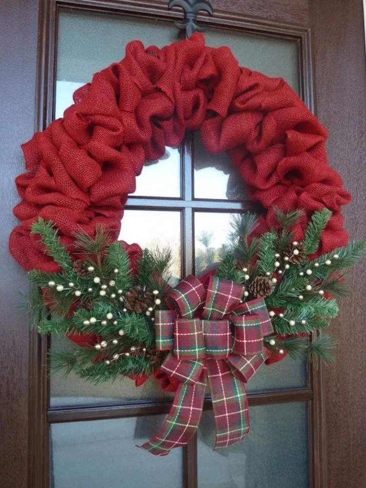 Farmhouse entryway displaying a ruffled burlap wreath with bright red accents under warm entry lights.