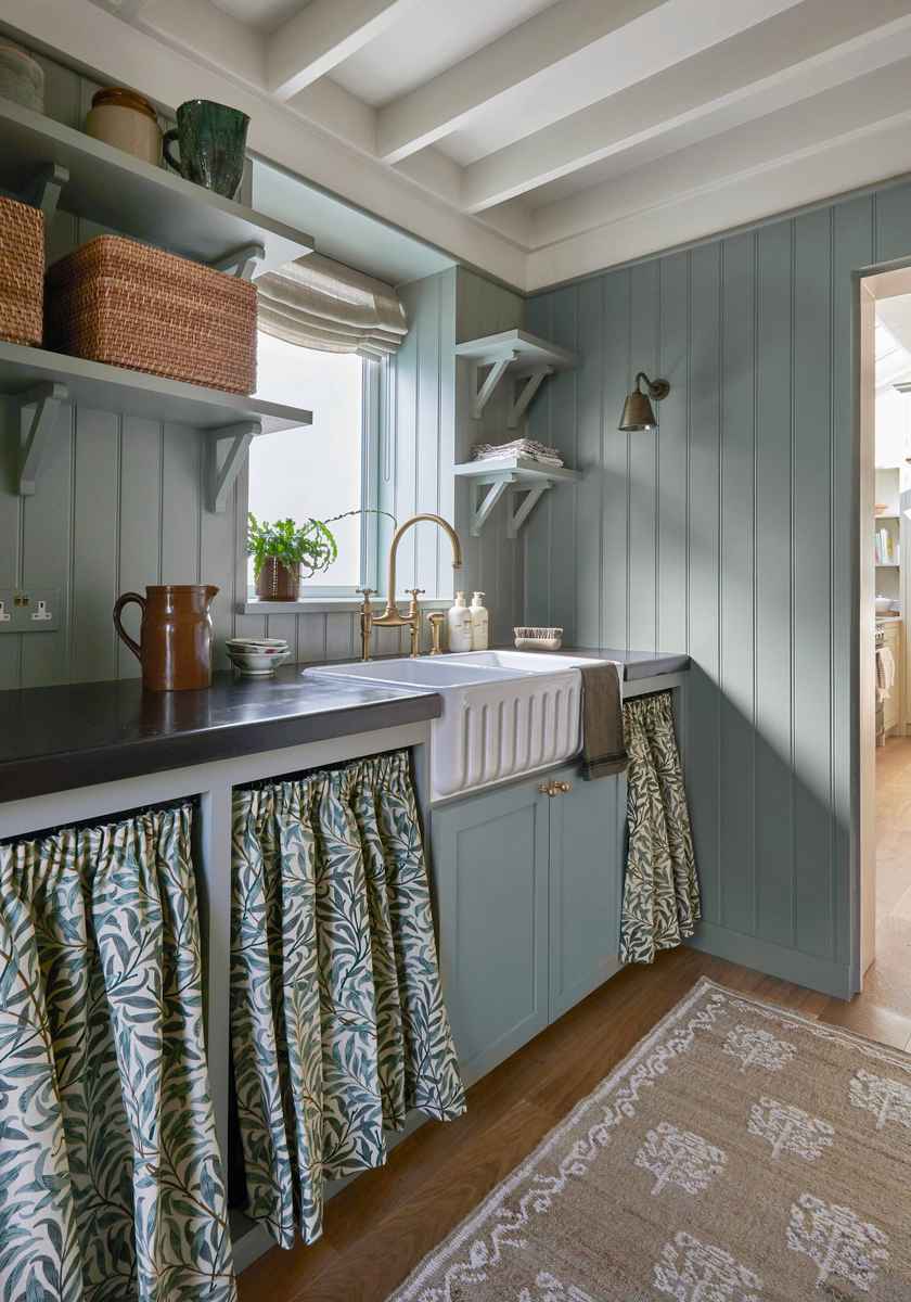 A cozy butler’s pantry featuring blue-gray beadboard walls and white wooden shelving.