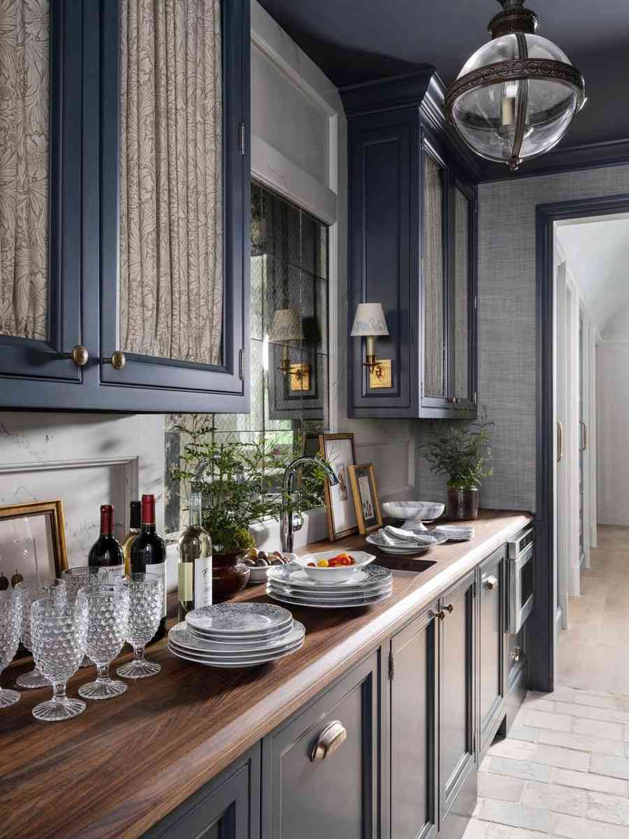 Elegant butler’s pantry with dark blue cabinets, glass door inserts, and organized glassware.