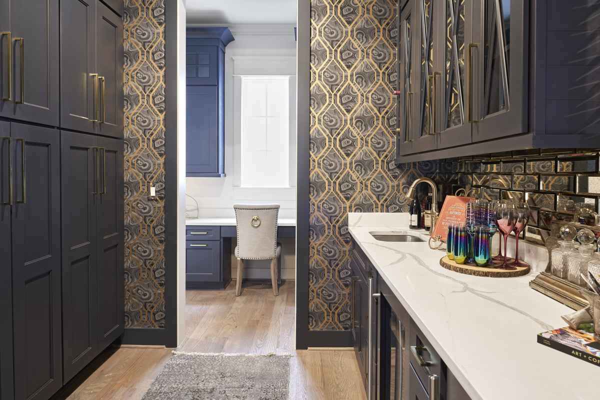 A luxury butler’s pantry with dark gray marble countertops, waterfall edges, and charcoal cabinetry.