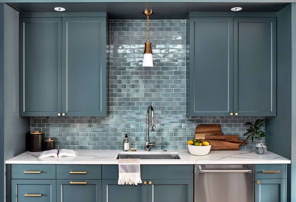 A functional butler’s pantry with gray-blue subway tiles and light gray cabinetry.