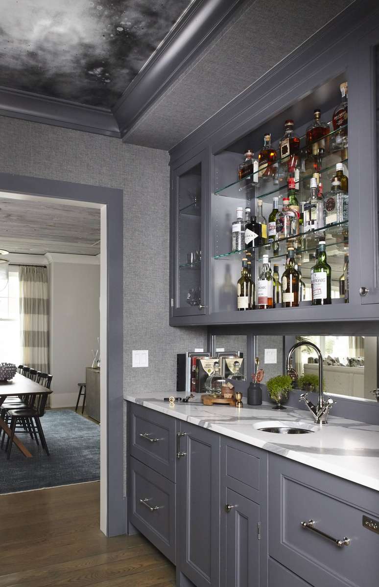 A chic gray butler’s pantry with frosted glass cabinet doors and organized shelving.