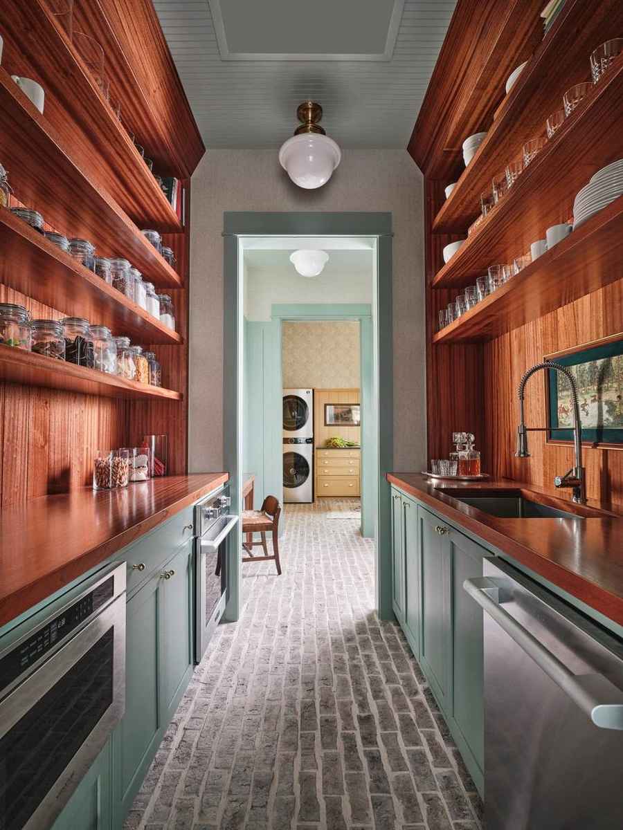 A vibrant butler’s pantry featuring sage green cabinets, brass hardware, and a galley layout.
