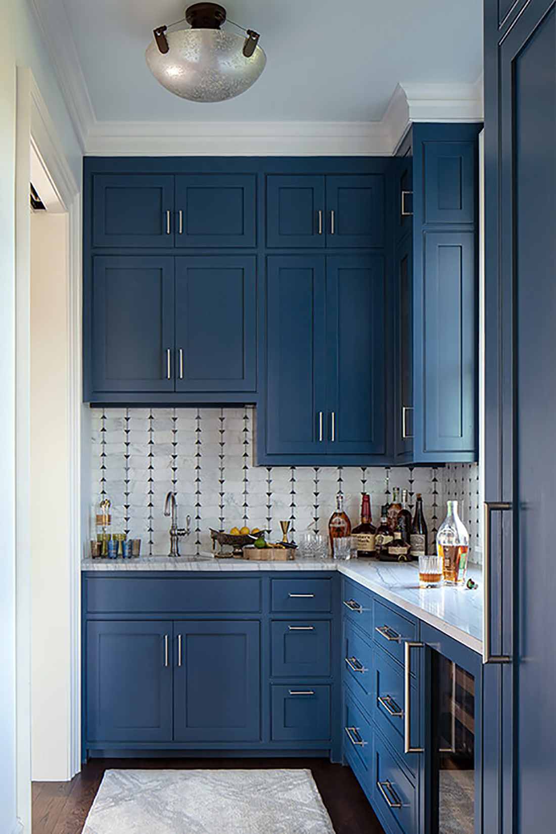 A monochromatic navy blue butler’s pantry with gold accents and high-gloss finishes.