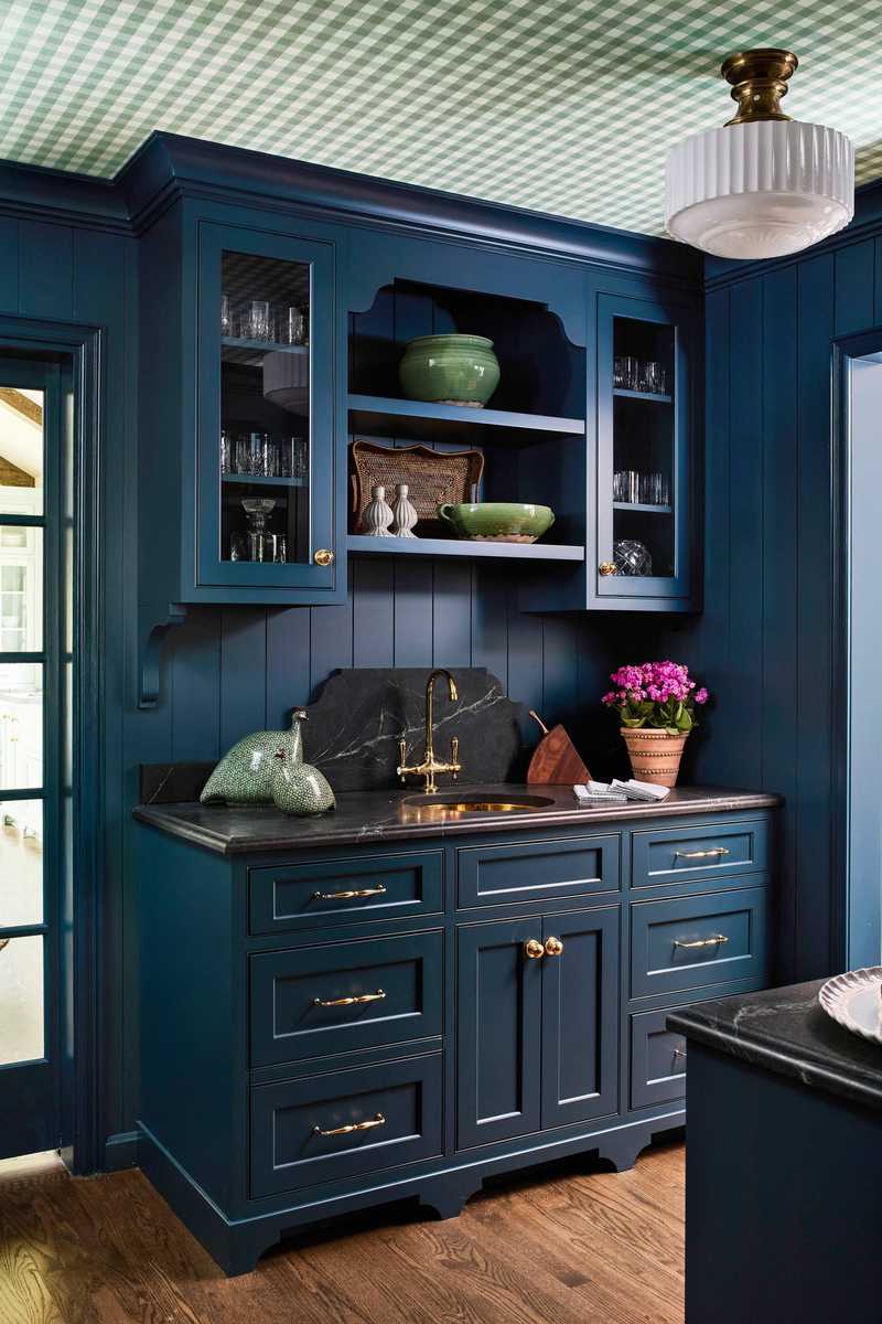 A butler’s pantry featuring navy blue base cabinets and natural wood open shelves.