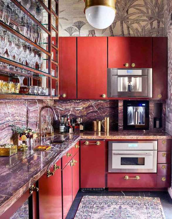 A vibrant butler’s pantry with deep red cabinets, white quartz counters, and gold hardware.