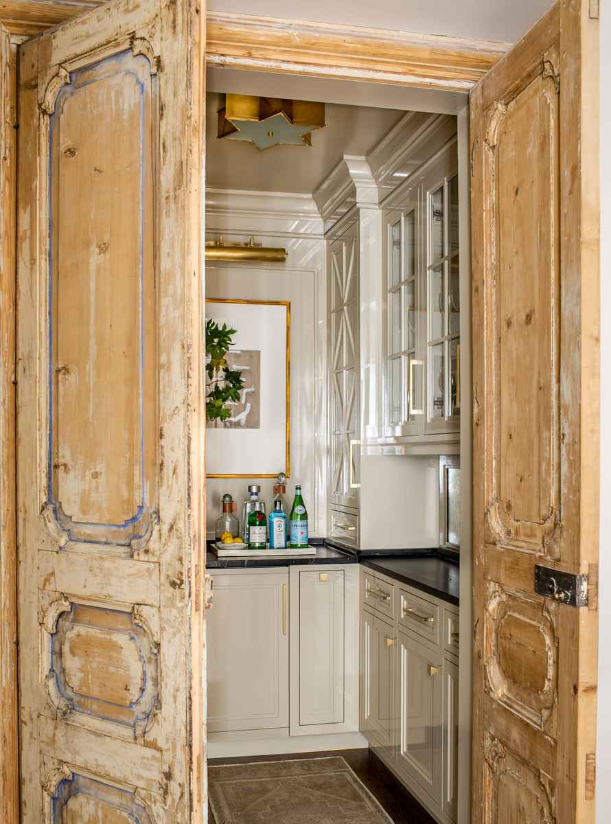 Butler's pantry featuring sliding rustic reclaimed wood doors and warm glowing accent lighting.