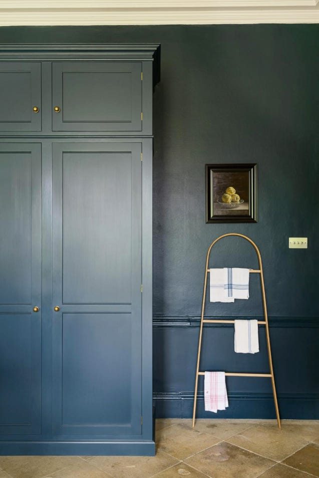 Sage green butler's pantry with tall vertical cabinets and a brass rolling library ladder.