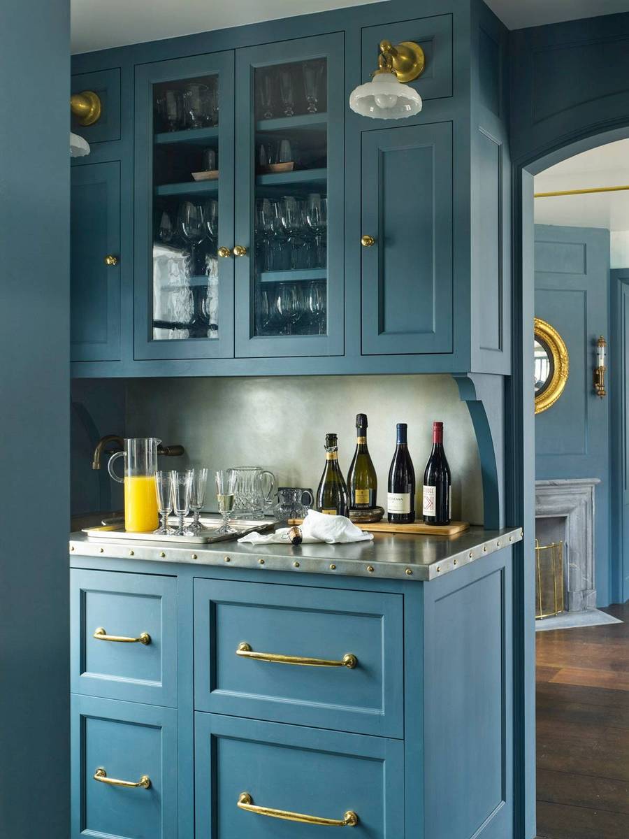 Moody teal butler's pantry cabinets adorned with gleaming satin brass hardware and marble countertops.