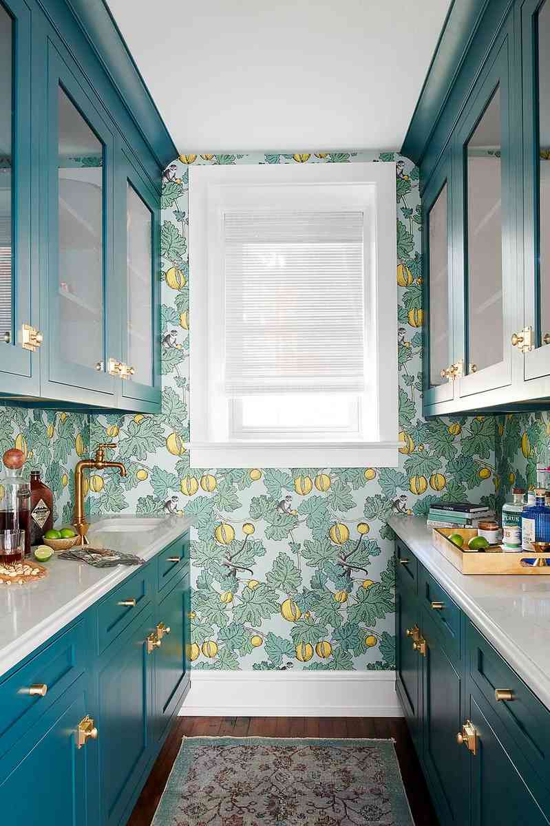 Elegant teal floral wallpaper lining a butler's pantry with dark cabinets and polished brass details.
