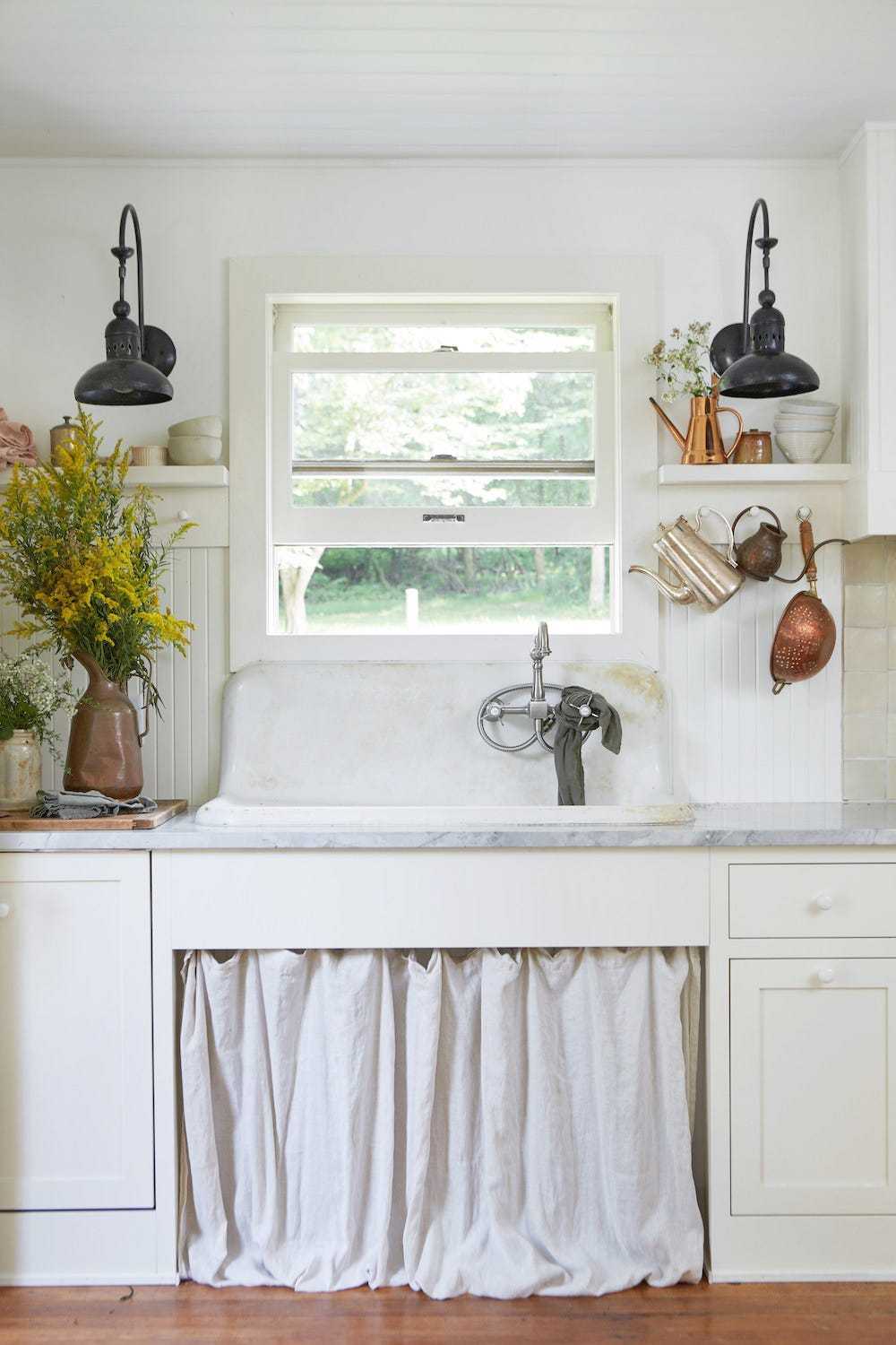 Cozy white farmhouse butler's pantry with a pleated fabric curtain skirt under the counter.