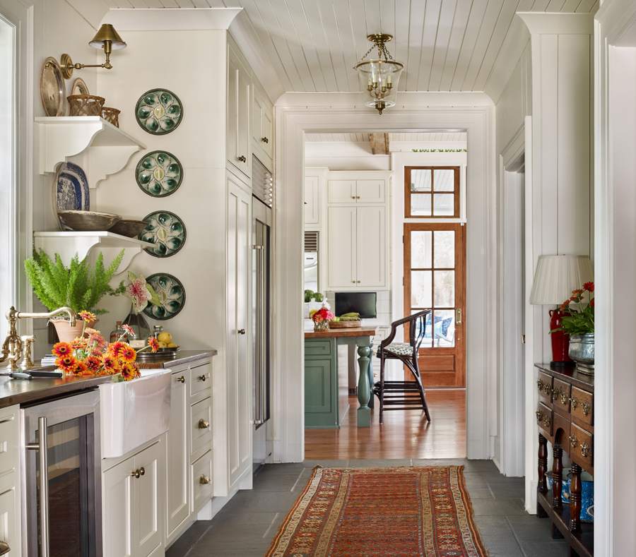 Bright white butler's pantry organized with open floating shelves displaying ceramic dinnerware and glassware.