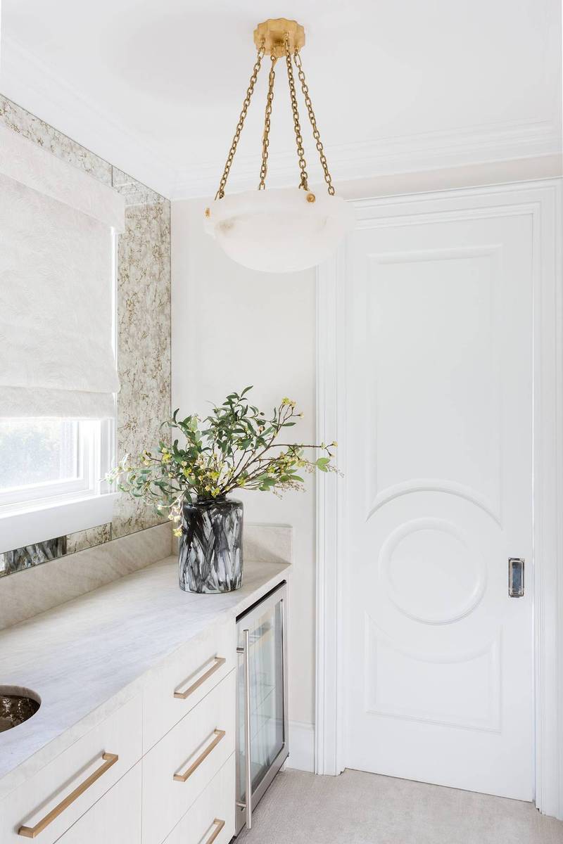 White butler's pantry featuring a striking white dome pendant light over marble prep counters.