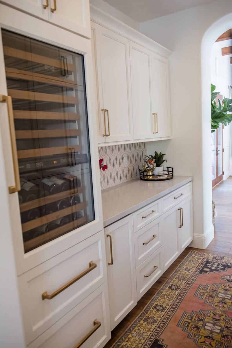 Seamless white butler's pantry featuring an integrated wine fridge framed by white cabinetry and quartz counters.