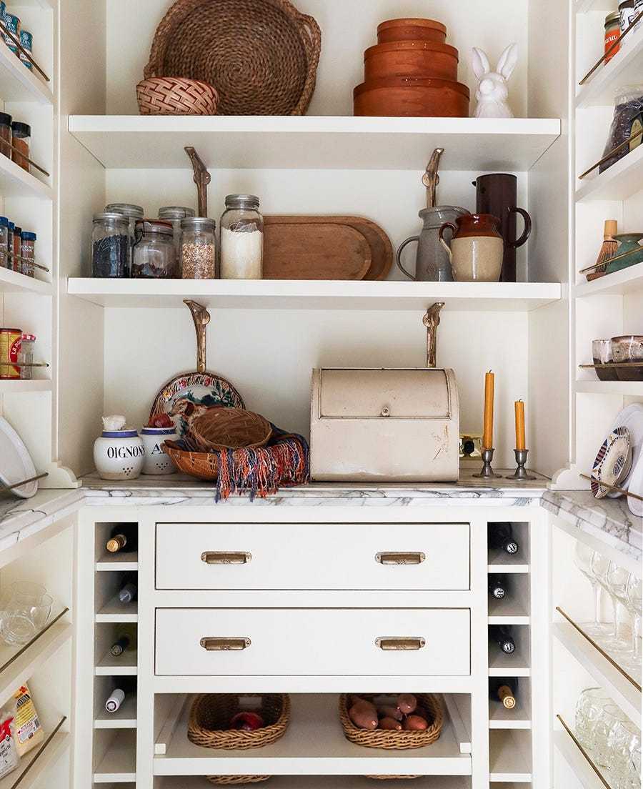 Custom built-in white wood wine rack inside a butler's pantry storing horizontal wine bottles.