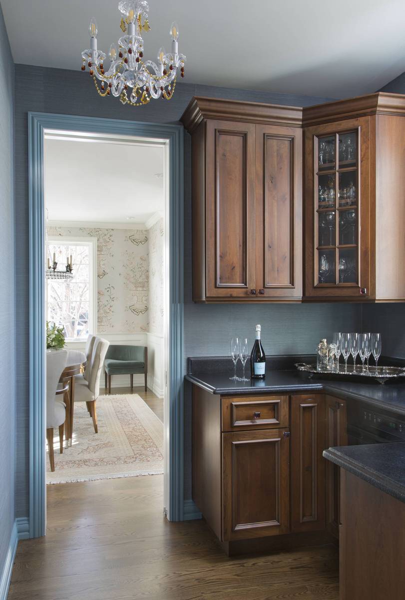 Elegant butler's pantry featuring warm stained oak wood cabinets and sleek dark granite countertops.