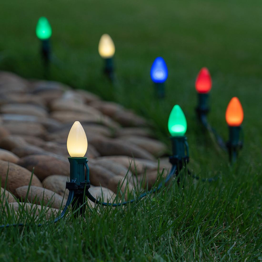 Exterior pathway decorated with C7 bulb stakes, stone walkway, snowy landscape, and warm light.
