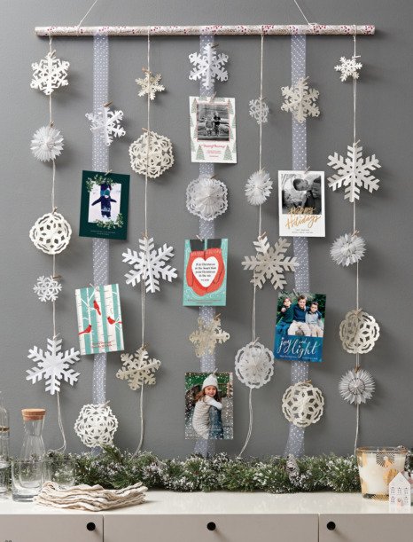 Scandinavian living room showing dark walnut leaning ladder wrapped in fairy lights holding cards.