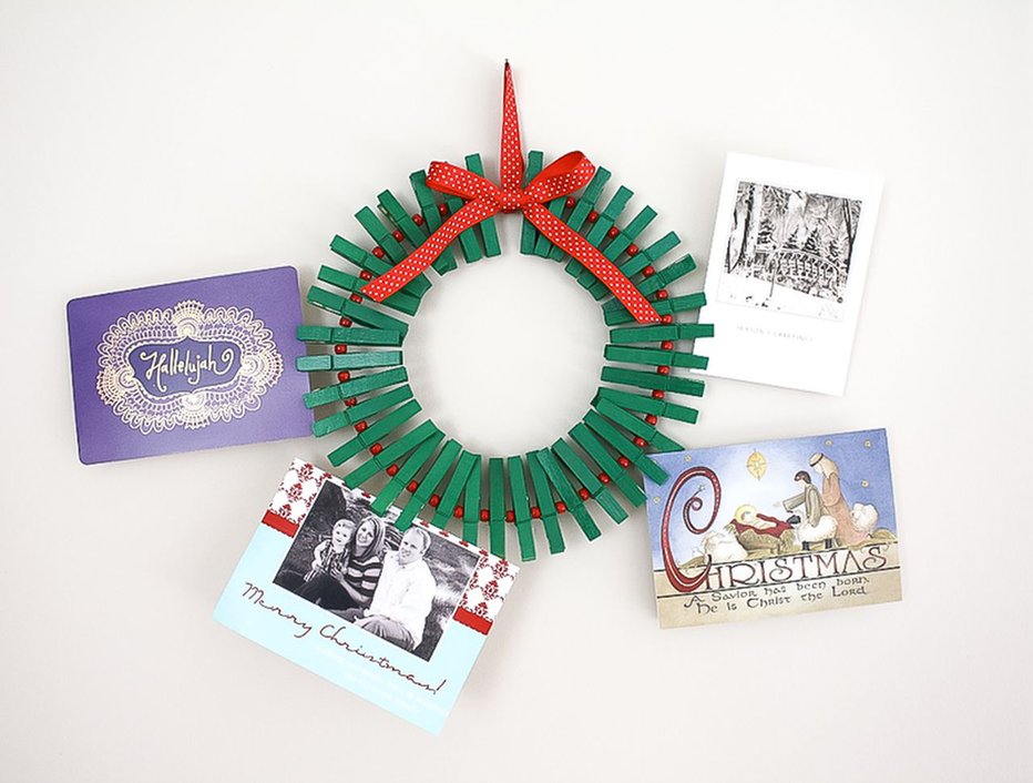 Interior farmhouse door showing circular wooden clothespin wreath pinned with cards and dried florals.