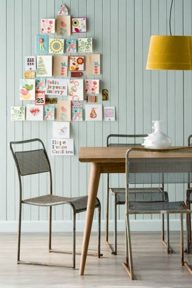 Living room accent wall showing cards arranged into large Christmas tree shape topped with brass star.
