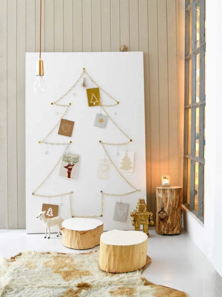 Urban loft brick wall with draped brass chains forming Christmas tree shape holding holiday cards.