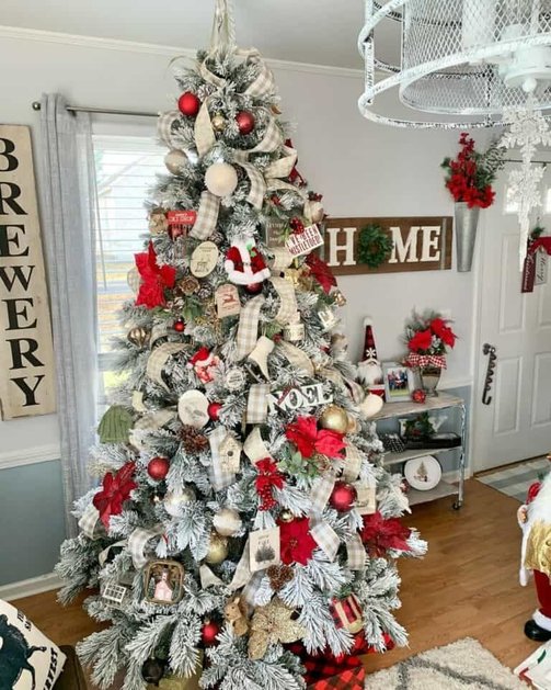 Traditional great room tree adorned with gold checkered ribbon, leather accent chairs, glowing lighting