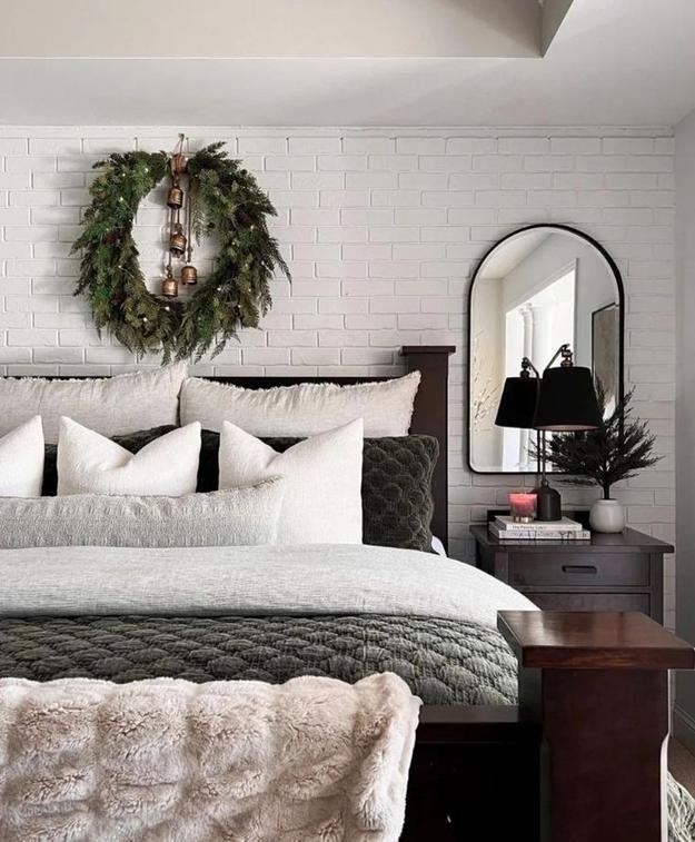 Dark green bedroom walls with brass accents, white bedding, and pinecone decor