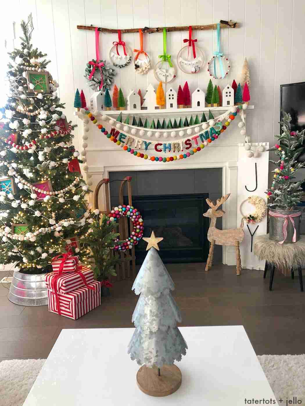 Traditional mantelpiece decorated with mini pine tree, stockings, wood textures, warm string lights.