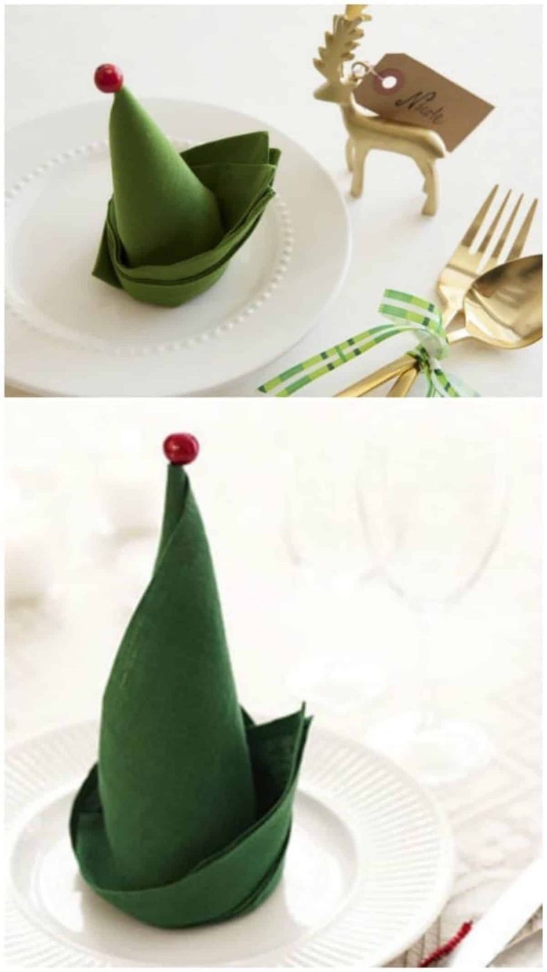 Dining table place setting with green felt napkin folded like an elf hat, festive plates.