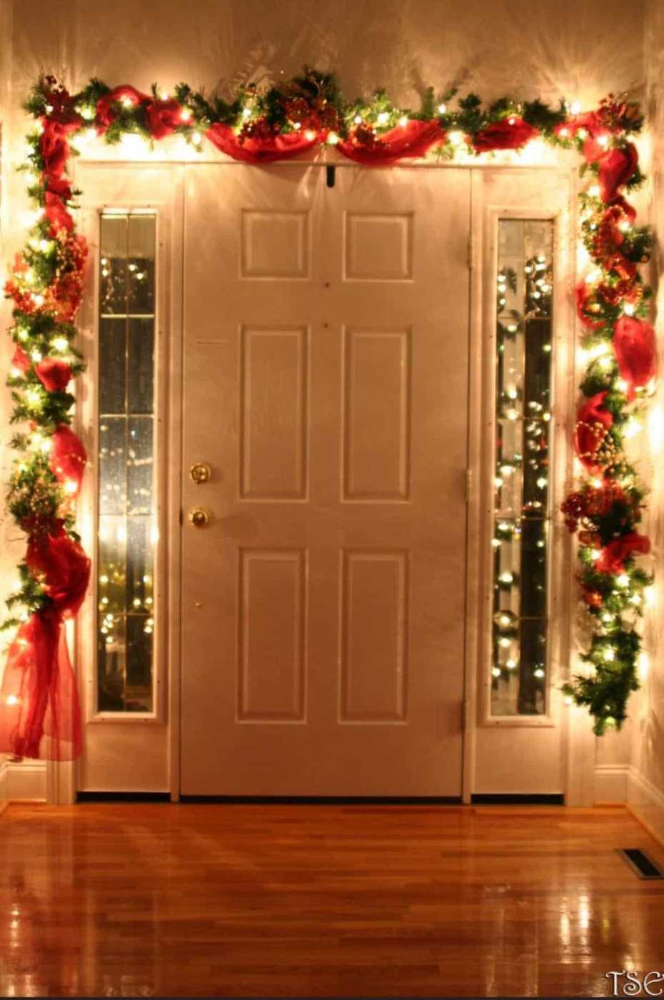 Exterior front door with thick pine garland, warm lanterns, welcoming holiday entrance.