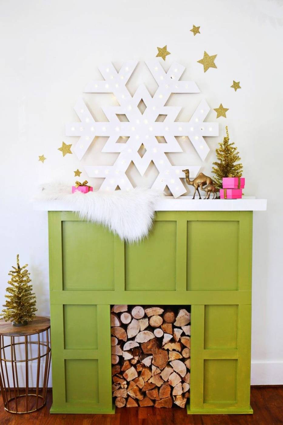 Modern fireplace mantel with large snowflake decor, white candles, neutral color scheme.