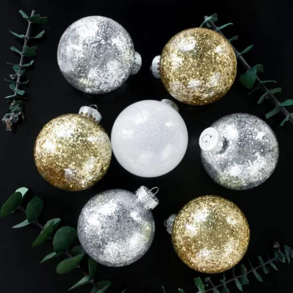 Elegant Christmas tree with metallic gold and silver glitter ornaments, warm fairy lights.
