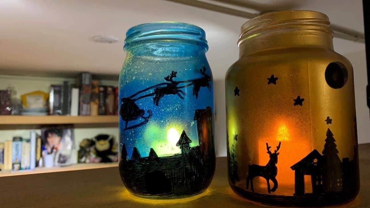 A collection of mason jars painted with festive holiday scenes and illuminated from within.